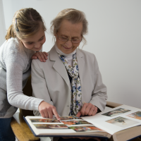 Grootmoeder kijkt met kleindochter naar oud fotoalbum om te digitaliseren